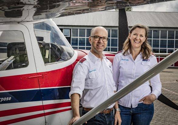 Links de neus van een rood/wit/blauw gestreept vliegtuigje, en daarvoor een pilotenstel