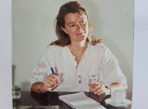 Thea Westerbeek in haar jonge jaren aan tafel met een blocnote en een pen en een kop koffie tijdens een interview met Dien de Haan